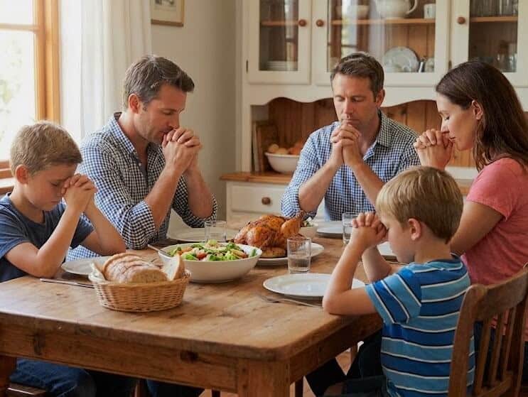Family praying around a table before eating a meal